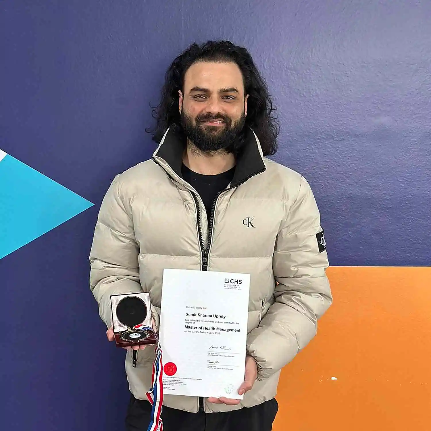 CHS student Sumit Sharma Uprety standing, smiling, and holding the College Medal of Academic Excellence